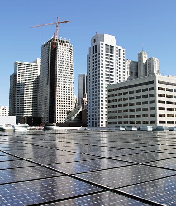 Rooftop solar panel installation with city skyscrapers in the background, showcasing commercial solar energy solutions by Castaways Energy