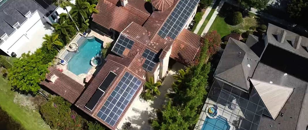 Aerial view of a solar array on a very large home with a swimming pool.