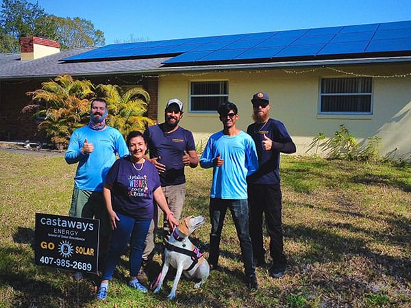 A family is smiling in their front yard after having solar installed on their home.