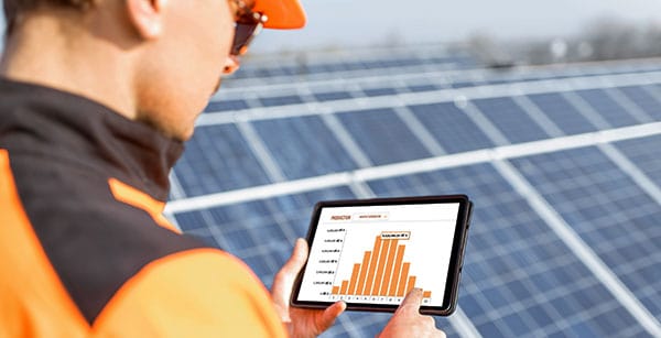 Technician analyzing solar panel performance data on a tablet, provided by Castaways Energy, ensuring optimal solar energy production.