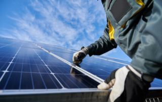 Technician installing solar panels under a clear blue sky