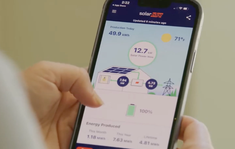 Modern home with rooftop solar panels, Tesla Powerwall batteries, and EV charging station at dusk