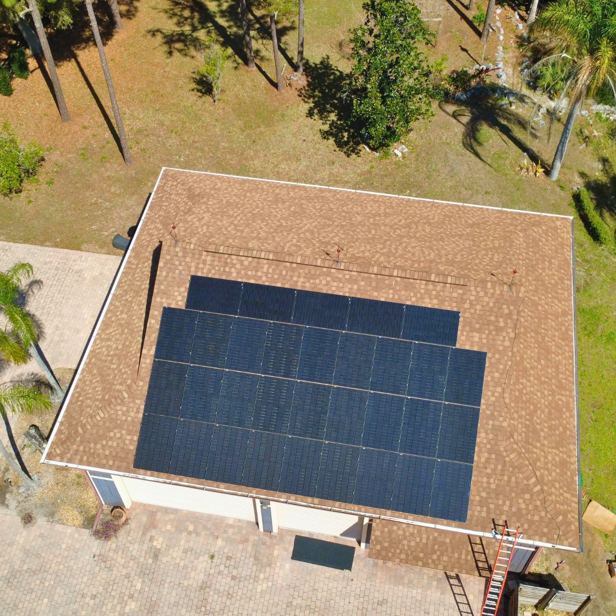 2 Drone view of a Castaways Energy solar panel installation on a Florida home with a large asphalt shingle roof and tropical landscaping.