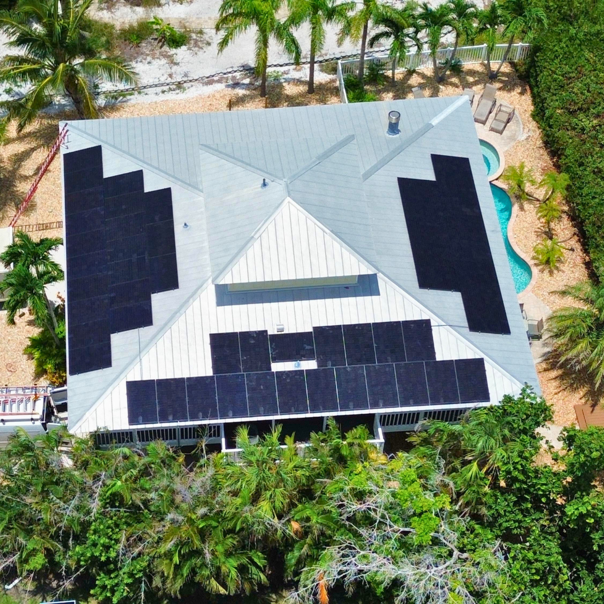 3 Aerial view of a Castaways Energy residential solar project on a Florida metal roof with multiple solar arrays, palm trees, and a backyard pool.