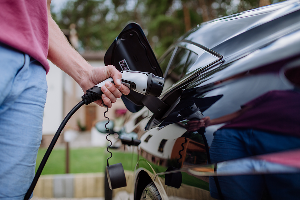 Person plugging an electric vehicle into a home EV charger installed by Castaways Energy